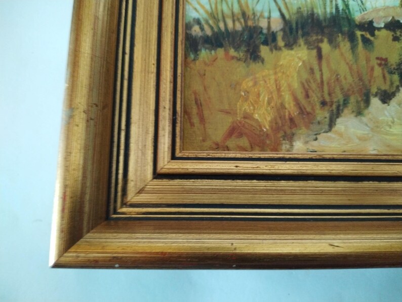 May include: A gold-colored picture frame with a black inner border. The frame is made of wood and has a slightly distressed finish.