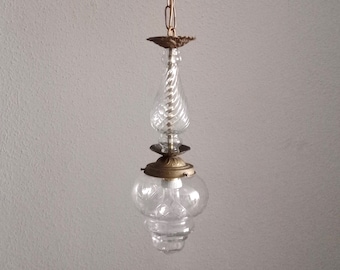 Op de afbeelding: Een vintage glazen en messing kroonluchter met een heldere glazen kap en een spiraalvormige glazen hanger.