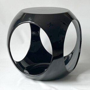 K&ouml;nnte beinhalten: Ein schwarzer, gl&auml;nzender, geometrischer Beistelltisch mit einem einzigartigen, dreidimensionalen Design. Der Tisch hat drei offene Kreise, die einen modernen und stilvollen Look erzeugen.