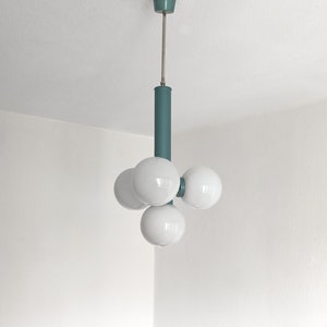 Puede incluir: Una l&aacute;mpara de techo de color turquesa con cuatro bombillas blancas en forma de globo.