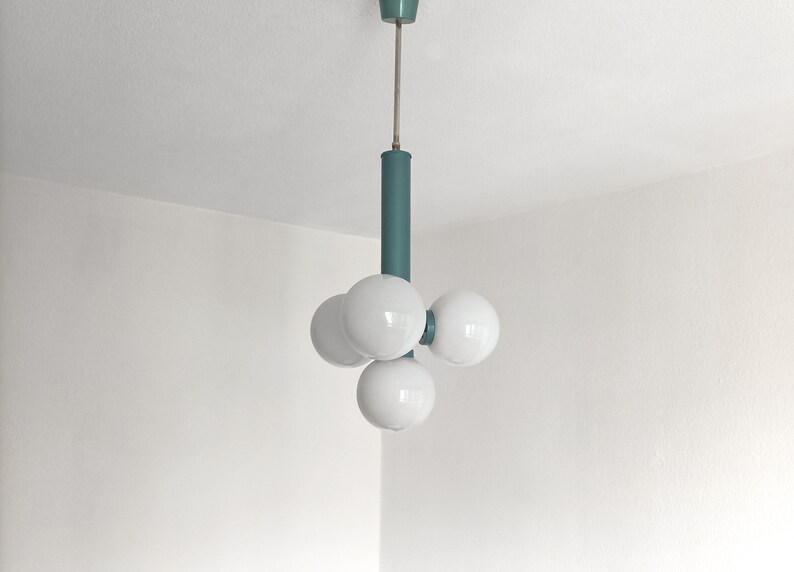 Puede incluir: Una l&aacute;mpara de techo de color turquesa con cuatro bombillas blancas en forma de globo.