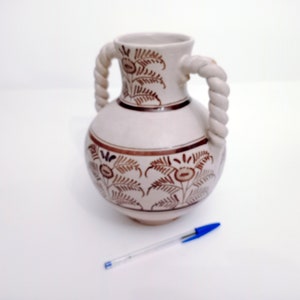 May include: White ceramic vase with brown floral design and rope-like handles.