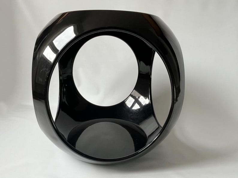 K&ouml;nnte beinhalten: Eine schwarze Keramikskulptur mit einer kugelf&ouml;rmigen Form und drei sich schneidenden kreisf&ouml;rmigen &Ouml;ffnungen. Die Skulptur hat eine gl&auml;nzende Oberfl&auml;che.