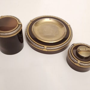 Może przedstawiać: Zestaw trzech vintage brązowych i złotych popielniczek z wzorem sznurka. Popielniczki są wykonane z metalu i mają okrągły kształt.