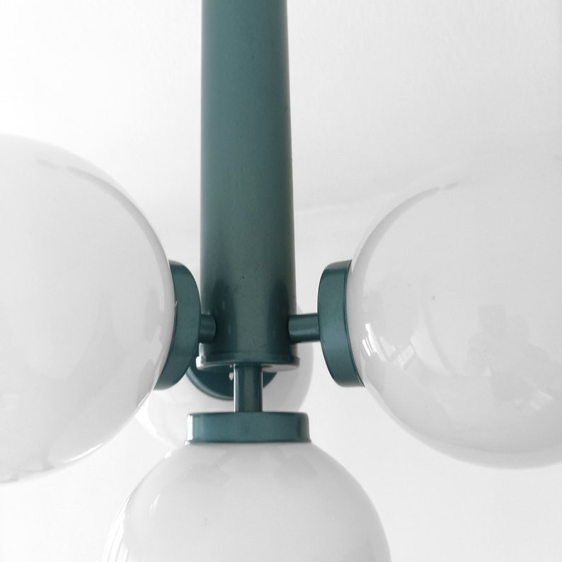 Puede incluir: Una l&aacute;mpara de techo de color verde azulado con cuatro bombillas blancas en forma de globo.