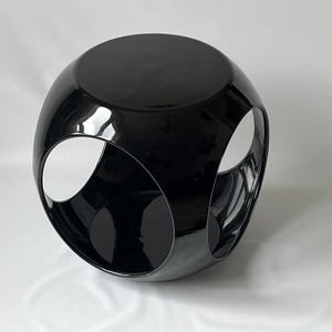K&ouml;nnte beinhalten: Ein schwarzer, gl&auml;nzender, geometrischer Beistelltisch mit drei offenen Kreisen. Der Tisch ist kugelf&ouml;rmig.