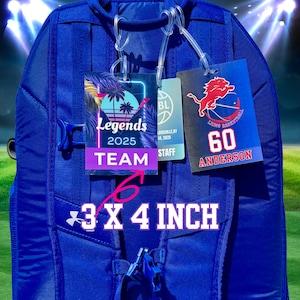 May include: A blue backpack with three tags attached. One tag reads "Legends 2025 TEAM" with a palm tree graphic. Another tag says "Lions Basketball 60 ANDERSON". The tags are 3 x 4 inches.