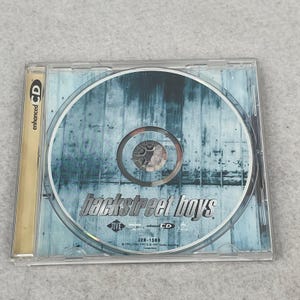 May include: A Backstreet Boys music CD in a clear plastic jewel case. The disc features a light blue and white textured background with the band name printed in black. The Jive logo, enhanced CD text, and catalog number J2B-1589 are visible on the disc.