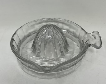 Exprimidor de cítricos vintage de vidrio transparente con boquilla y mango.
