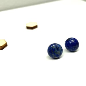 May include: A pair of round, blue lapis lazuli earrings with gold flecks.
