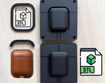May include: Two black 3D printed moulds for making a case for a pair of wireless earbuds. The moulds are open on one side and have a raised lip around the edge. The moulds are sitting on a light wood surface. There is a brown leather case for the earbuds and a file icon with the text "STL" on it.