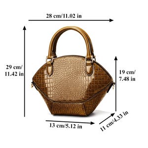 Peut inclure: Sac &agrave; main marron brillant avec un motif peau de crocodile. Le sac a une poign&eacute;e sup&eacute;rieure et mesure 29 cm de haut, 28 cm de large et 19 cm de profondeur. La base mesure 13 cm de large et 11 cm de profondeur.