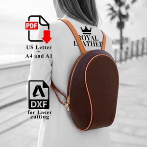 May include: A brown leather backpack with a rounded shape and a gold zipper. The backpack has tan trim and straps. The text "ROYAL LEATHER" is visible on the back. Also visible are PDF and DXF icons with text for laser cutting.