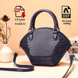 Peut inclure: Un sac &agrave; main violet fonc&eacute; avec une texture en peau de crocodile, dot&eacute; d'une poign&eacute;e sup&eacute;rieure et d'une bandouli&egrave;re amovible. Le sac a une quincaillerie dor&eacute;e et le texte "US Letter + A4 and A1" et "DXF for Laser cutting".