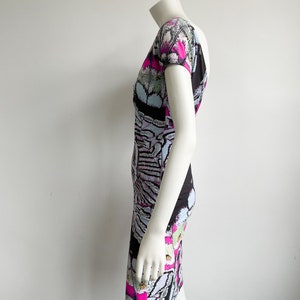 K&ouml;nnte beinhalten: Ein kurz&auml;rmliges Kleid mit Rundhalsausschnitt in einem Muster aus Schwarz, Wei&szlig;, Pink und Blau.