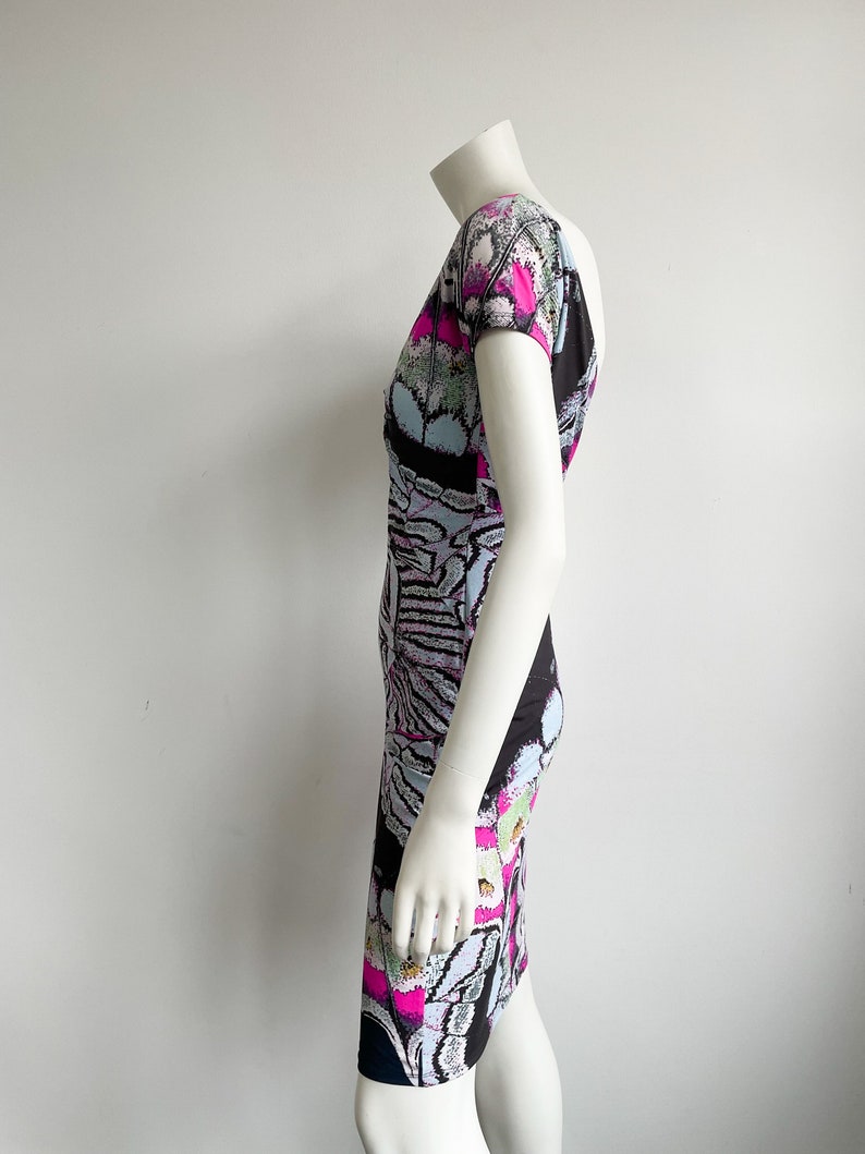 K&ouml;nnte beinhalten: Ein kurz&auml;rmliges Kleid mit Rundhalsausschnitt in einem Muster aus Schwarz, Wei&szlig;, Pink und Blau.