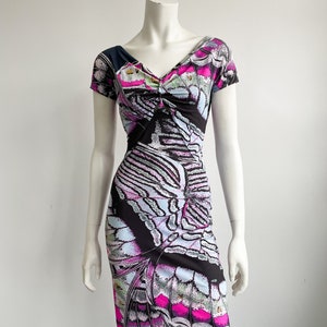 K&ouml;nnte beinhalten: Ein schwarzes, pinkfarbenes und blaues Kleid mit einem Schmetterlingsmuster. Das Kleid hat einen V-Ausschnitt und kurze &Auml;rmel.