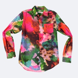 May include: A long-sleeve button-down shirt with a vibrant, abstract pattern. The shirt features a colorful design with shades of pink, green, orange, and blue. It has a chest pocket and a classic collar. The cuffs and collar are green.