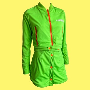 May include: A bright green two-piece outfit with a zip-up jacket and a skirt. The jacket has a red zipper and the skirt has a button closure. The jacket has the word "*LOVE*" embroidered on the right side of the chest.