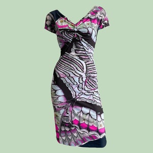 K&ouml;nnte beinhalten: Ein schwarzes, wei&szlig;es und pinkfarbenes Kleid mit einem Schmetterlingsmuster. Das Kleid hat einen V-Ausschnitt und kurze &Auml;rmel.