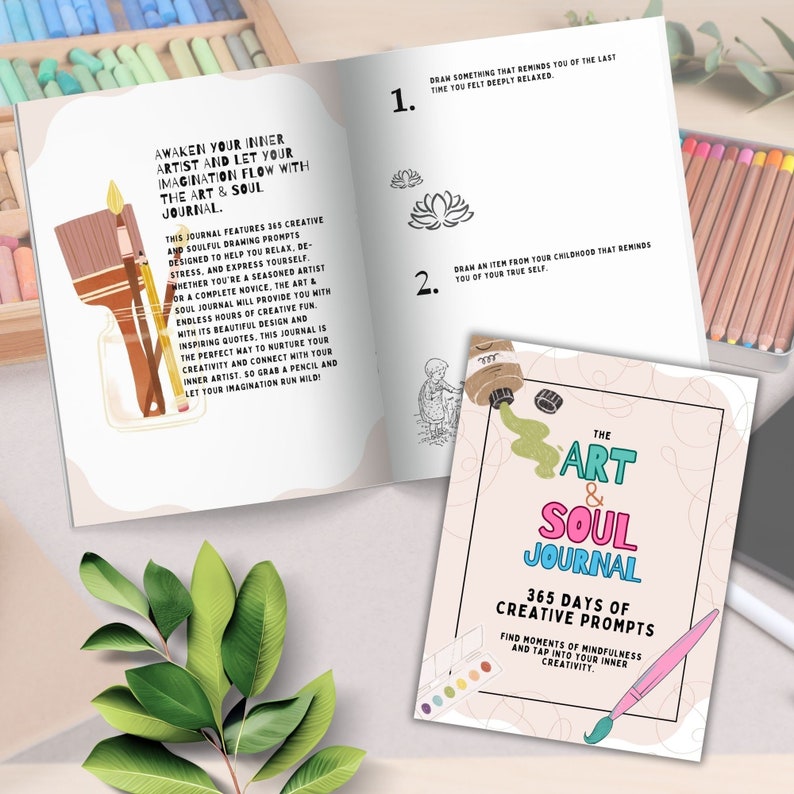 May include: A pink and white journal with the title "The Art & Soul Journal" and the text "365 Days of Creative Prompts". The journal cover features a paintbrush and a paint palette with colorful paint.