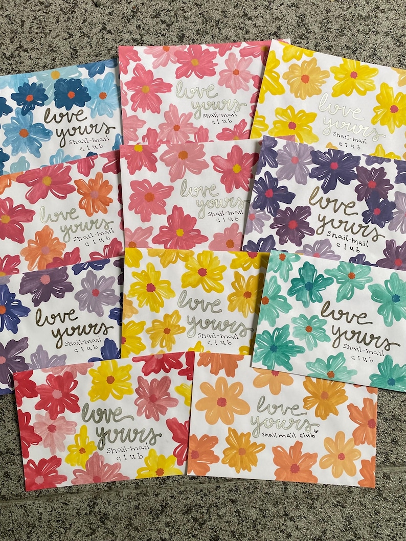 May include: A collection of ten rectangular envelopes featuring various floral patterns in shades of blue, pink, yellow, purple, teal, and orange. Each envelope displays the handwritten text "love yours snail-mail club" in a cursive script.
