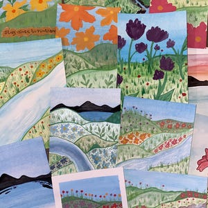 May include: A collection of rectangular art prints featuring hand-painted landscapes with rolling green hills, winding blue rivers, and various colorful flowers. One print includes the text Stay close to nature in brown script lettering.