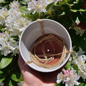 Puede incluir: Una maceta colgante de cer&aacute;mica blanca con un inserto de terracota marr&oacute;n y cuerda para colgar. La maceta est&aacute; vac&iacute;a y lista para una planta.