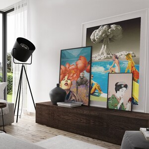 May include: A living room interior with a wooden shelf displaying three framed art prints. The prints feature a collage of a woman with flowers, a scene of people swimming in a pool with an atomic bomb explosion in the background, and a traditional Japanese woman in a kimono.