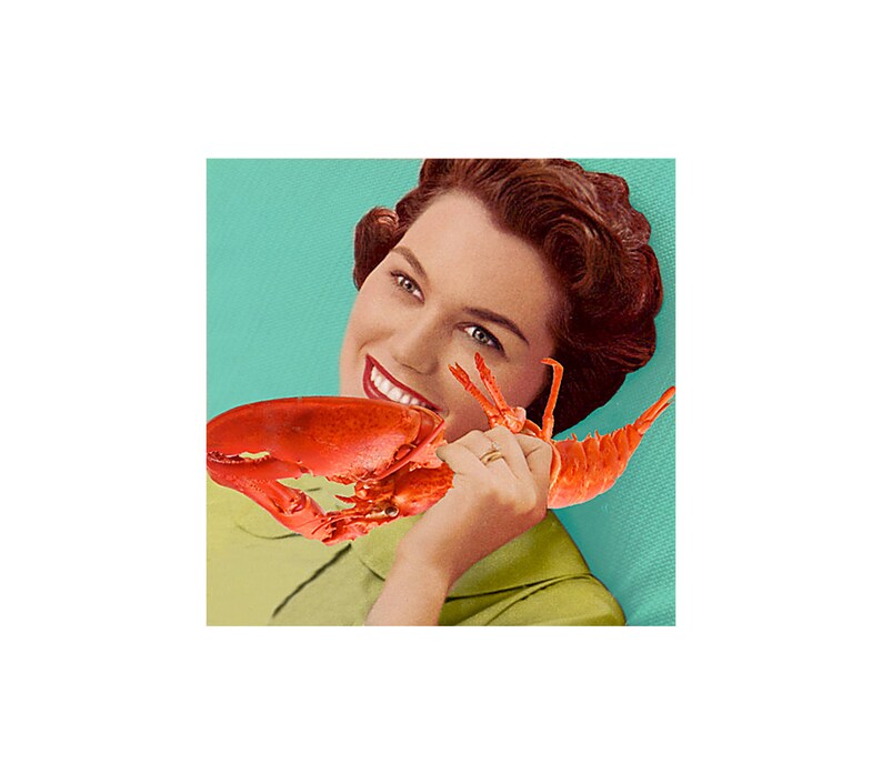 May include: A woman with red hair is holding a red lobster in front of her mouth. She is smiling and looking at the camera. The background is a light blue color.