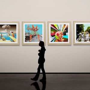 May include: Four framed art prints displayed on a white wall. The prints feature a variety of colorful and abstract designs. A person is walking in front of the wall, looking at the art.
