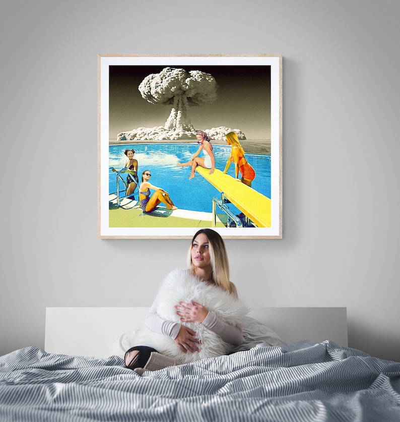 May include: A framed print of a vintage style collage featuring four women in swimsuits at a pool with a mushroom cloud in the background.