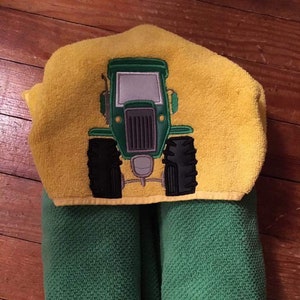 May include: A green and yellow hooded towel with a green tractor embroidered on the hood.