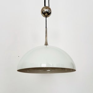 Peut inclure: Un luminaire suspendu en forme de dôme blanc avec une tige en métal argenté et une boule argentée suspendue au plafond.