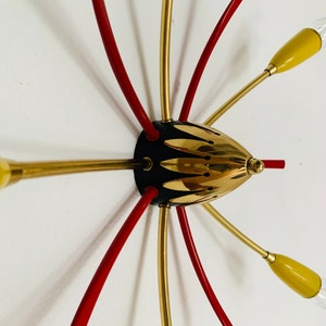 May include: A gold and red mid-century modern ceiling light fixture with six arms and yellow glass shades.
