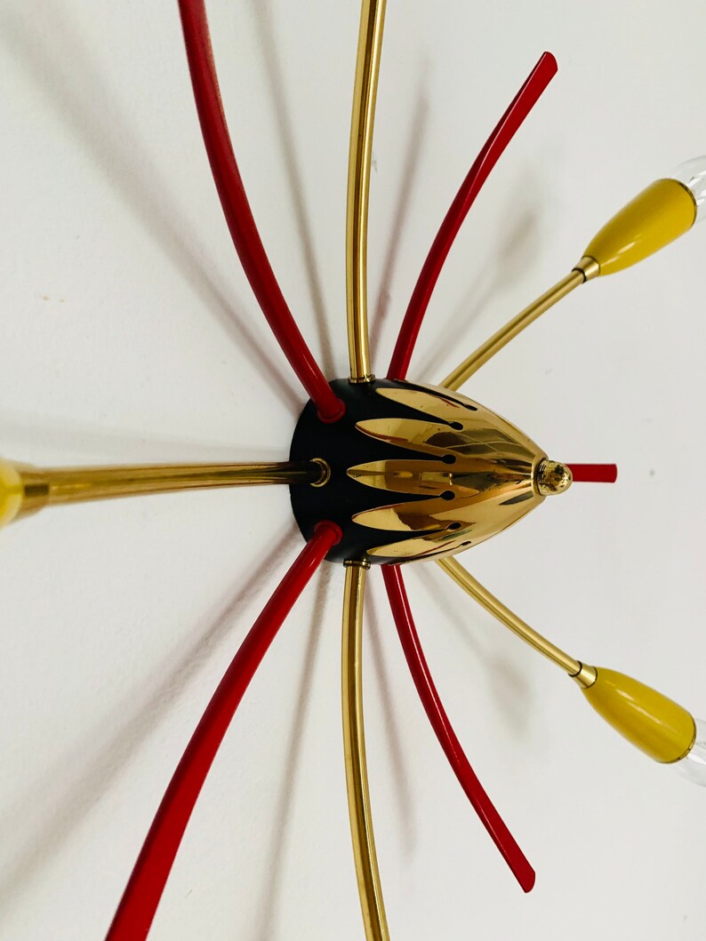 May include: A gold and red mid-century modern ceiling light fixture with six arms and yellow glass shades.
