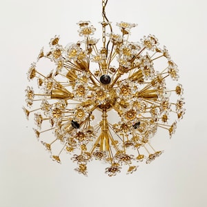 Puede incluir: Una lámpara de araña de tono dorado con forma esférica y muchos acentos de flores de cristal. La lámpara de araña tiene una cadena que cuelga del techo.