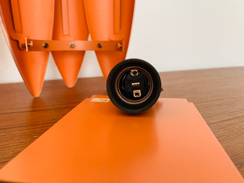 May include: Close-up of a black electrical socket with a metal center. The socket is on a wooden surface.