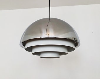 May include: A modern pendant light fixture with a polished, silver-colored dome and white, tiered, circular shades. The light hangs from a black cord, creating a sleek, contemporary design. This ceiling light is suitable for various interior styles.