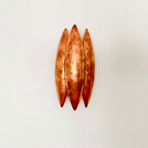 May include: Three copper-colored, elongated, teardrop-shaped wall sconces.