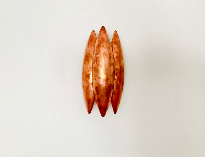 May include: Three copper-colored, elongated, teardrop-shaped wall sconces.