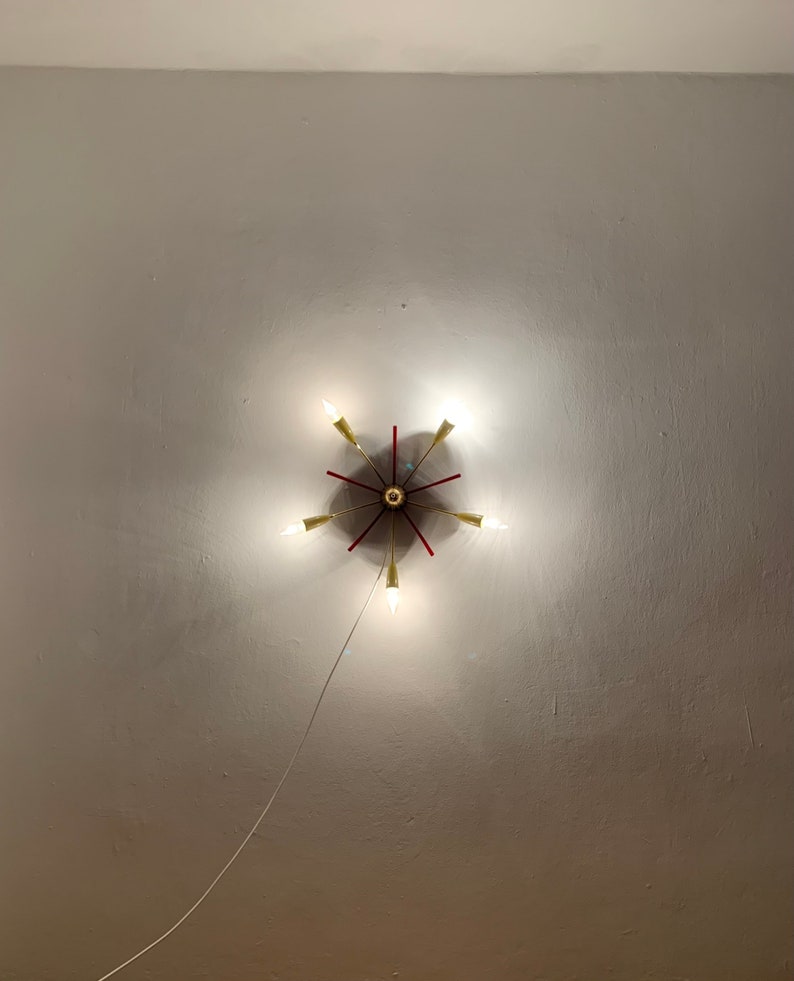 May include: A gold and red ceiling light fixture with six light bulbs. The light fixture is mounted on a white ceiling.