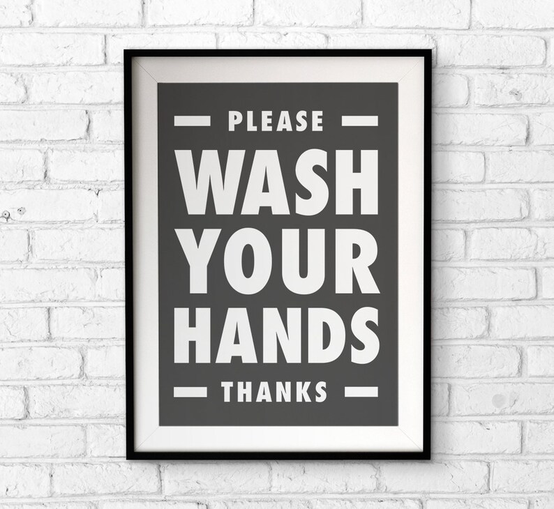 Puede incluir: Un cartel enmarcado con un borde negro y un paspart&uacute; blanco. El cartel tiene un fondo gris oscuro con las palabras "PLEASE WASH YOUR HANDS THANKS" en letras may&uacute;sculas blancas grandes. El cartel est&aacute; colgado en una pared de ladrillos blancos.