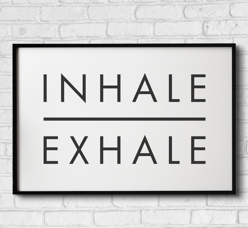 Op de afbeelding: Zwart-wit ingelijste print met de tekst "INHALE EXHALE" in een minimalistische stijl.