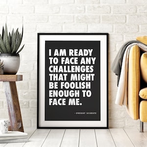 May include: Black and white framed print with a quote from the TV show "The Office" by Dwight Schrute: "I am ready to face any challenges that might be foolish enough to face me."