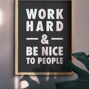 Puede incluir: Un p&oacute;ster motivacional en blanco y negro enmarcado con el texto "WORK HARD & BE NICE TO PEOPLE" en letras blancas.