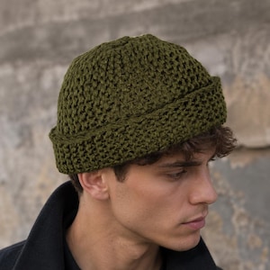 Può includere: Un berretto all'uncinetto color verde oliva con un bordo spesso ripiegato. Il cappello presenta un motivo testurizzato a maglia aperta su tutta la corona e sul risvolto, offrendo un aspetto coerente. Il berretto è realizzato in filato.