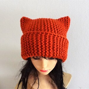 May include: A bright orange knitted beanie with cat ears. The beanie is made of a soft, warm yarn and is perfect for keeping your head and ears warm in the winter.