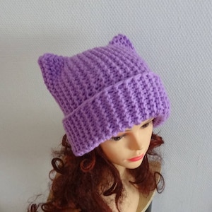 May include: A purple knitted hat with cat ears. The hat is made of a soft, warm yarn and is perfect for keeping your head and ears warm in the winter.