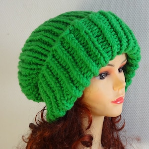 May include: A bright green knitted beanie with a slouchy fit. The beanie is made with a thick yarn and has a cable knit pattern.